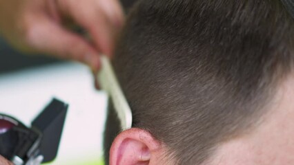 barber using clippers to cut a young man's hair