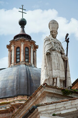 Fototapeta na wymiar Urbino, Italy - 2023, May 5: Saint Agostino statue, on the Santa Maria Assunta cathedral roof. In the background, the dome.