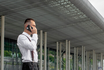 a handsome man nicely and stylishly dressed in pink glasses stands at a bus stop