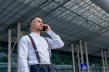 a handsome man nicely and stylishly dressed in pink glasses stands at a bus stop