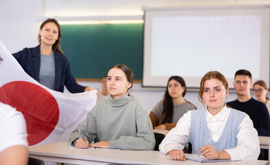 Young female students carefully writes down the lecture of the school teacher