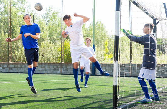 Youthful football players challenging for ball in goalmouth zone