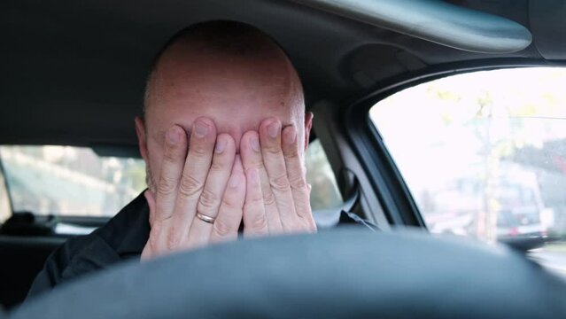 A man rubs his eyes while driving a car. Driver fatigue, long trip.
