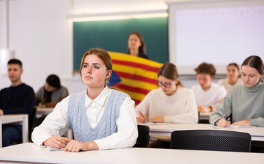 Students study in classroom, teacher stands behind with flag of Catalonia - obrazy, fototapety, plakaty