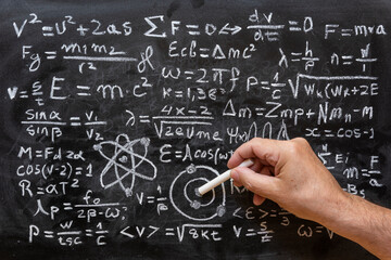 Mano humana señalando operaciones y formulas de física cuántica escritas con una tiza en la...