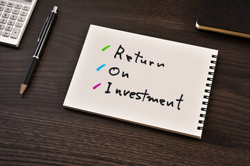 There is notebook with the word Return On Investment. It is as an eye-catching image.