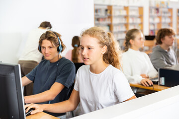 Fifteen-year-old schoolgirl, studying at school in an informatics lesson in the classroom, sitting at the computer