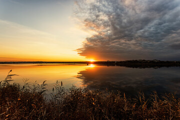 Warm sunset over a lake with dramatic clouds after a thunderstorm