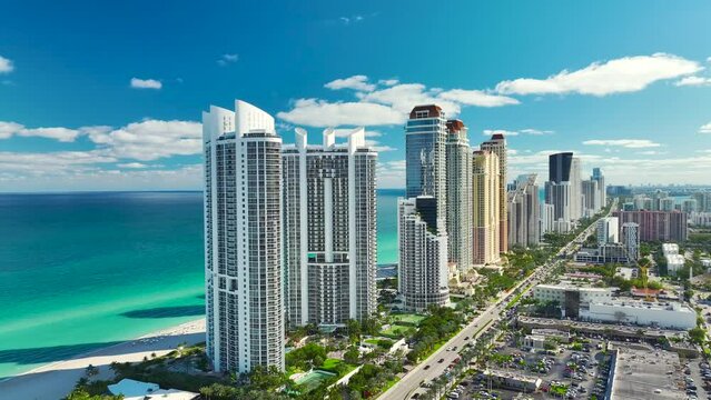 View from above of luxurious highrise hotels and condos on Atlantic ocean shore in Sunny Isles Beach city. Urban street with busy traffic. American tourism infrastructure in southern Florida