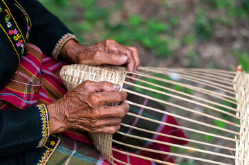 Close up Old man Hand weaving wicker basket or bamboo basketry  indoors.Weaving bamboo fish trap in...