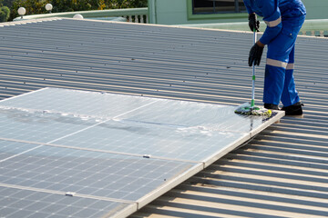 Man using a mop and water to clean the solar panels that are dirty with dust and birds' droppings...
