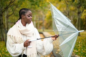 African woman closing the umbrella in autumn.