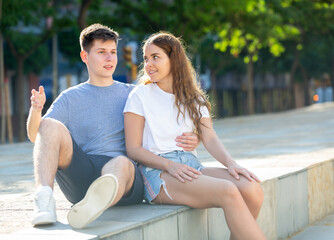 Young man is sitting with his girlfriend and hugging her