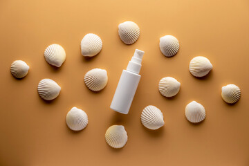 Plastic tube with sunscreen cream on beige background with seashells.