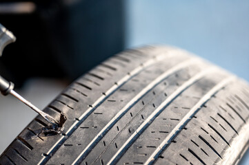 Repair plug being inserted to patch a nail tire puncture