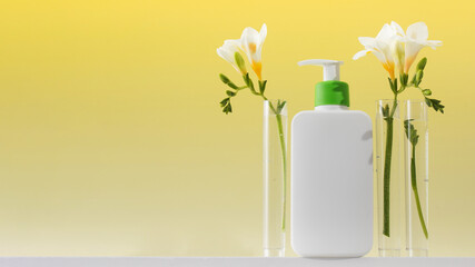 A mockup of a dispenser with a cosmetic skin care product with laboratory flasks and flowers. Copy space
