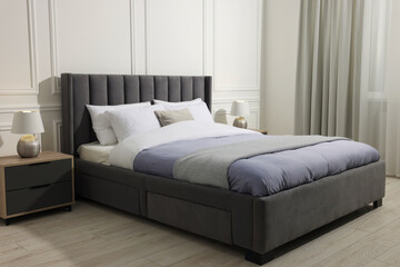 Comfortable bed between bedside tables with lamps at home. Interior design