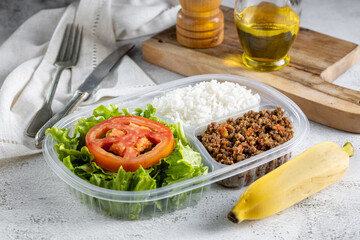 Lunchbox with lettuce salad with tomato, rice and ground beef.