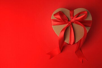 Beautiful heart shaped gift box with bow on red background, top view. Space for text