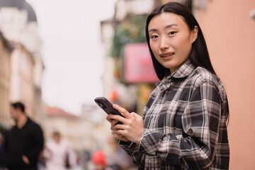 Portrait of a beautiful Korean woman on the old town street. Asian woman in casual clothes talking on the phone, modern technology and lifestyle.