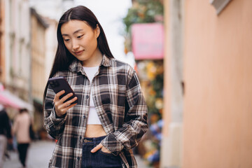 Portrait of a beautiful Korean woman on the old town street. Asian woman in casual clothes talking on the phone, modern technology and lifestyle.