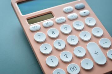 close up modern peach colour pastel calculator and white button on blue background, business and finance accounting concept