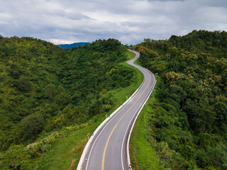 Taken from a drone camera angle at Sky Road, Road No. 3, Unseen, Nan Province, Thailand, meandering along the ridge of the forest. The view is very beautiful. The rainy season is green.