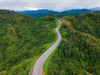 Obraz premium Taken from a drone camera angle at Sky Road, Road No. 3, Unseen, Nan Province, Thailand, meandering along the ridge of the forest. The view is very beautiful. The rainy season is green.