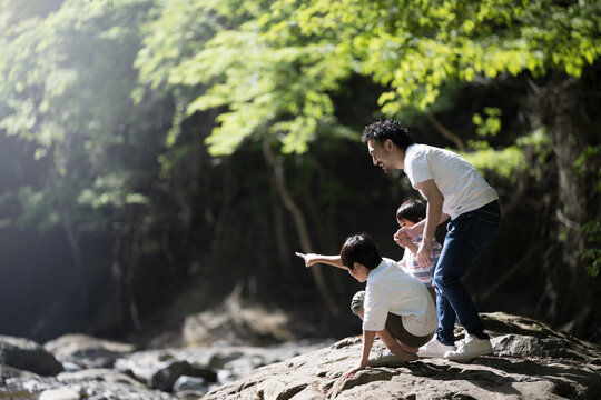 Image of summer vacation leisure and outdoor outing Asian parents and children playing in a river Wide angle
