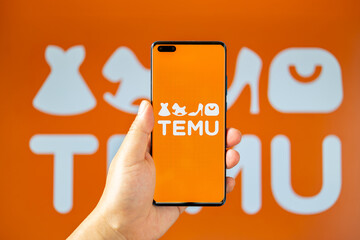 ZHONGSHAN China-June 15,2023:man holding a mobile with Temu logo at horizontal composition.