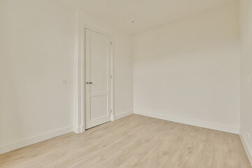 an empty room with white walls and wood floors, there is a door leading to the left side of the room