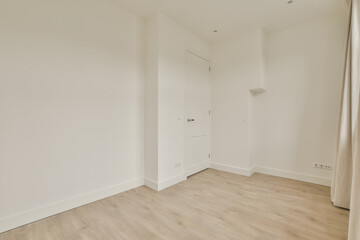 an empty room with white walls and wood flooring on the right side, there is a door in the corner to the left