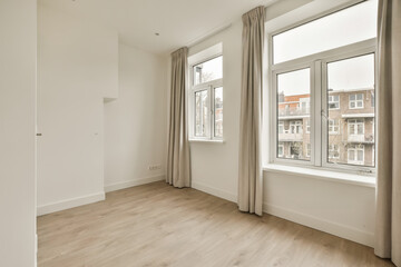 an empty room with wooden floors and white walls, there is a large window in the wall to the right