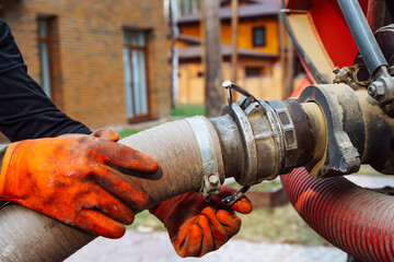 a hand connects a suction hose to a sewage tanker truck. Sewer pumping machine. Septic truck....