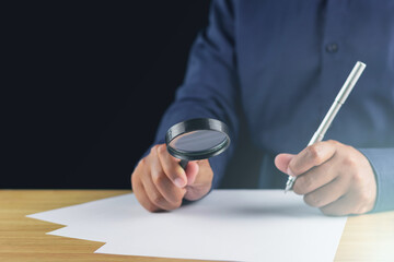 The man creates new idea by magnifying glass and pen. Research and development concept.