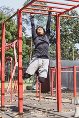 Young fit man climbing monkey bars during obstacle course in gym park