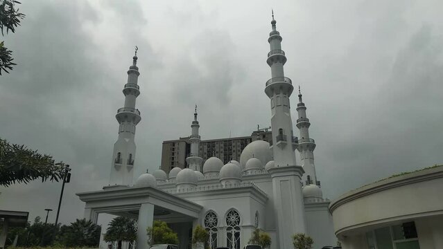 Static shot of At-Thohir Mosque with darken sky in the background, a magnificent white mosque located in the Podomoro Golf View area, Tapos, Depok, West Java, Indonesia