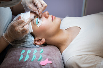 The master removes the composition for lamination from the client's eyelashes with a cotton swab....
