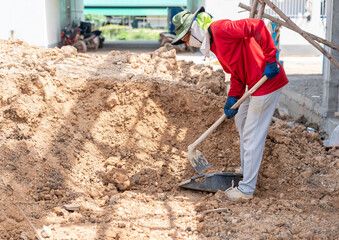 Worker with shovel loading soil in basket.