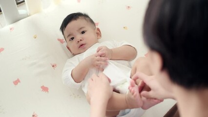 Top view mother wearing clothes after her baby changing diaper. Asian family mother’s day. Baby healthcare hygiene concept.
