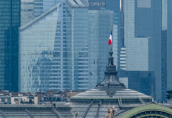 6 May 2023 Paris, France. The French flag is prominently displayed atop the Grand Palais with the modern day skyline of La Defense in the background. Grand Palais is an event venue for the 2024