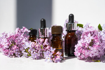Essential oil made from lilac. A bottle of lilac flower oil. Spa oil with lilac flowers. A bottle with aromatic oil and lilac flowers. Selective focus.