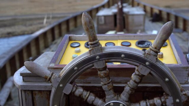 Old wooden ship wheel and yellow control panel dashboard, close up