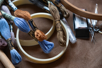 madejas de hilo de algodón en colores cafe y azul, sobre bastidores circulares y agujas para...