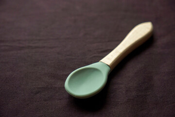Empty dishes for baby, soft shatterproof tableware for the first feeding,  spoon  for baby food on black texture background.