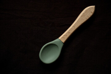 Empty dishes for baby, soft shatterproof tableware for the first feeding,  spoon  for baby food on black texture background.