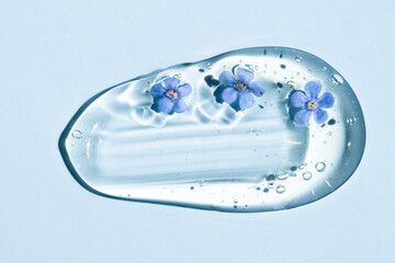 A sample of a liquid cosmetic texture for care with flowers in blue, top view.