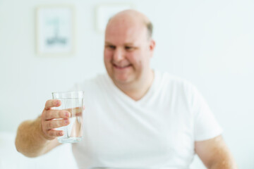 Caucasian white fat man drinks a water in a drinking glass in every morning.
