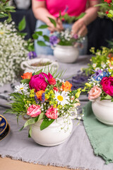 Gesteck aus frischen Blumen in einer Schale aus Keramik, Pfingstrose, Kamille, Margeriten, Clematis und Schleierkraut als Dekoration für den Tisch, Blumengesteck 