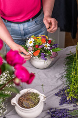 Florist bei der Arbeit, Frau steckt ein Blumengesteck aus frischen bunten Blumen in Gefäße aus Keramik